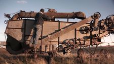 Artist John Lopez exploring a piece of old farm equipment