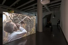 Sacha Braguine with rifle - Braguino Ou La Communauté Impossible at Le Bal in Paris