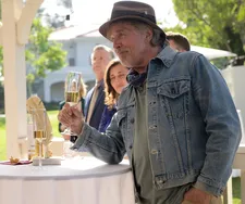 T Wasserman (Don Johnson) raises a glass