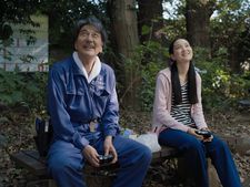 Hirayama (Kôji Yakusho) on his favourite bench with Niko (Arisa Nakano) looking up at the trees